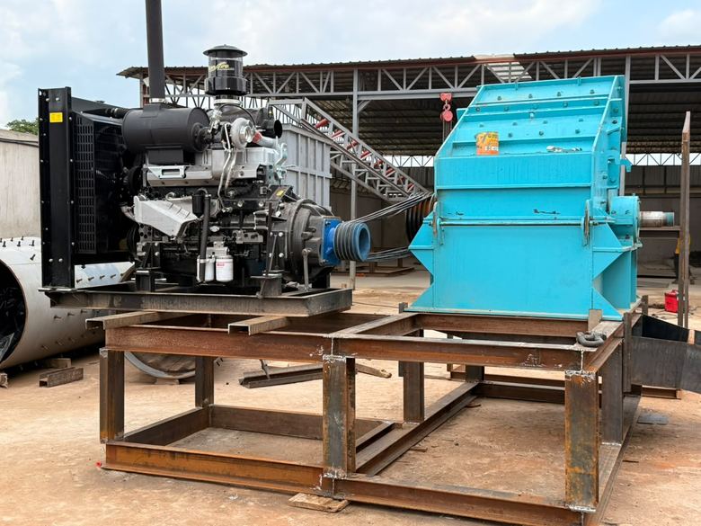 Broyeur bleu accouplé à un moteur, sur un bâti en acier, sous une charpente